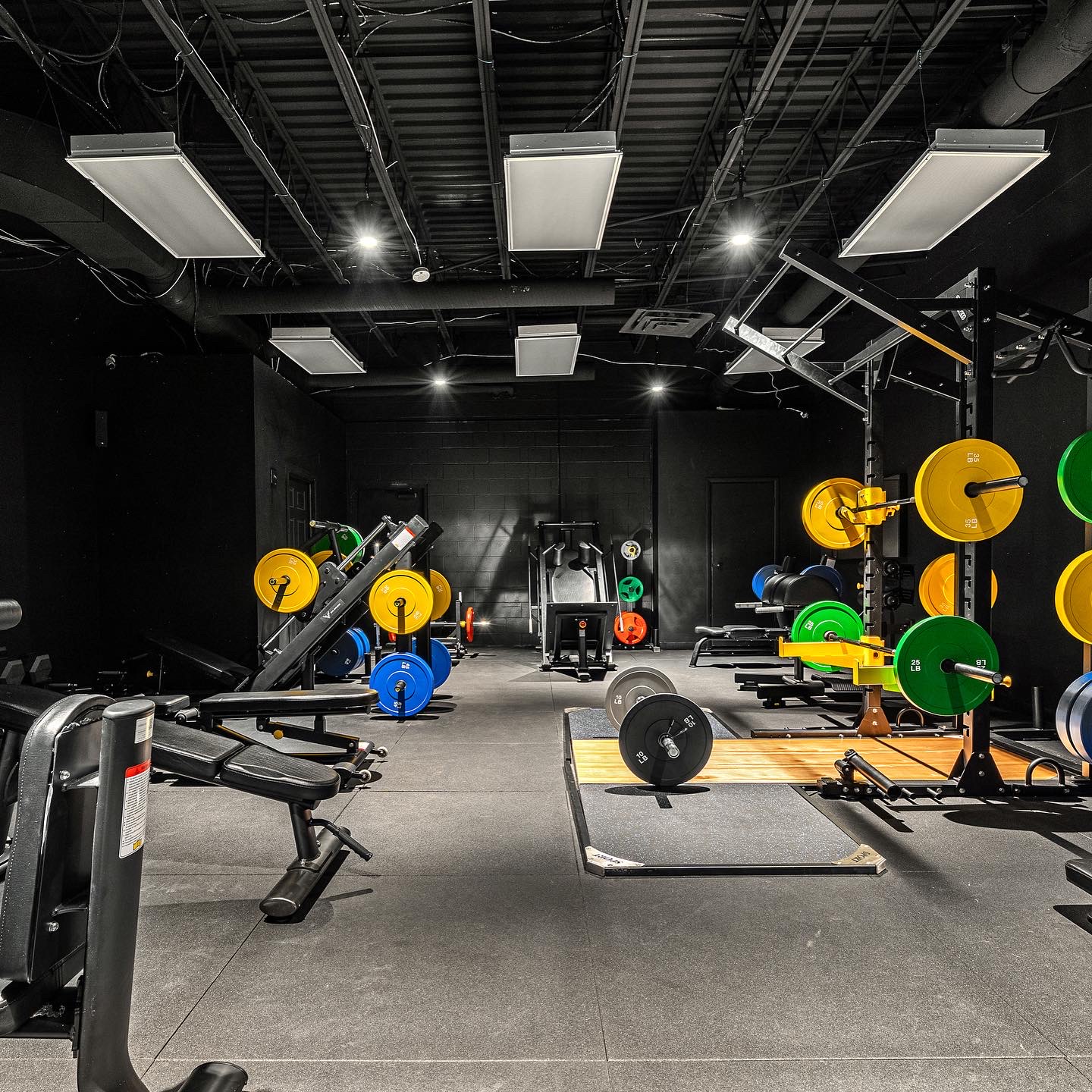 Loaded barbells with green, yellow, and blue bumper plates on lifting platform
