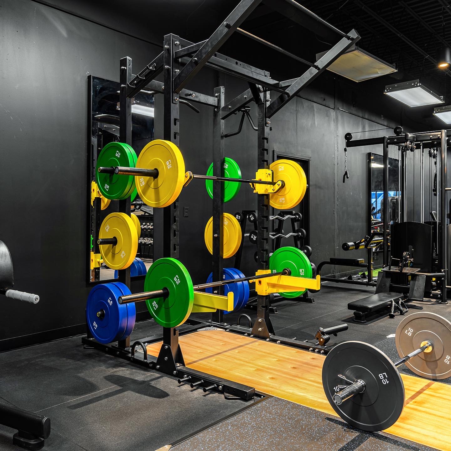 Power rack loaded with colored bumper plates over wooden lifting platform