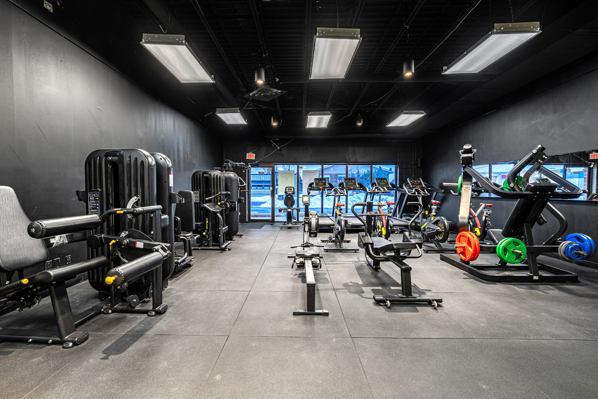 Selectorized machines and cardio deck facing front windows at sunset
